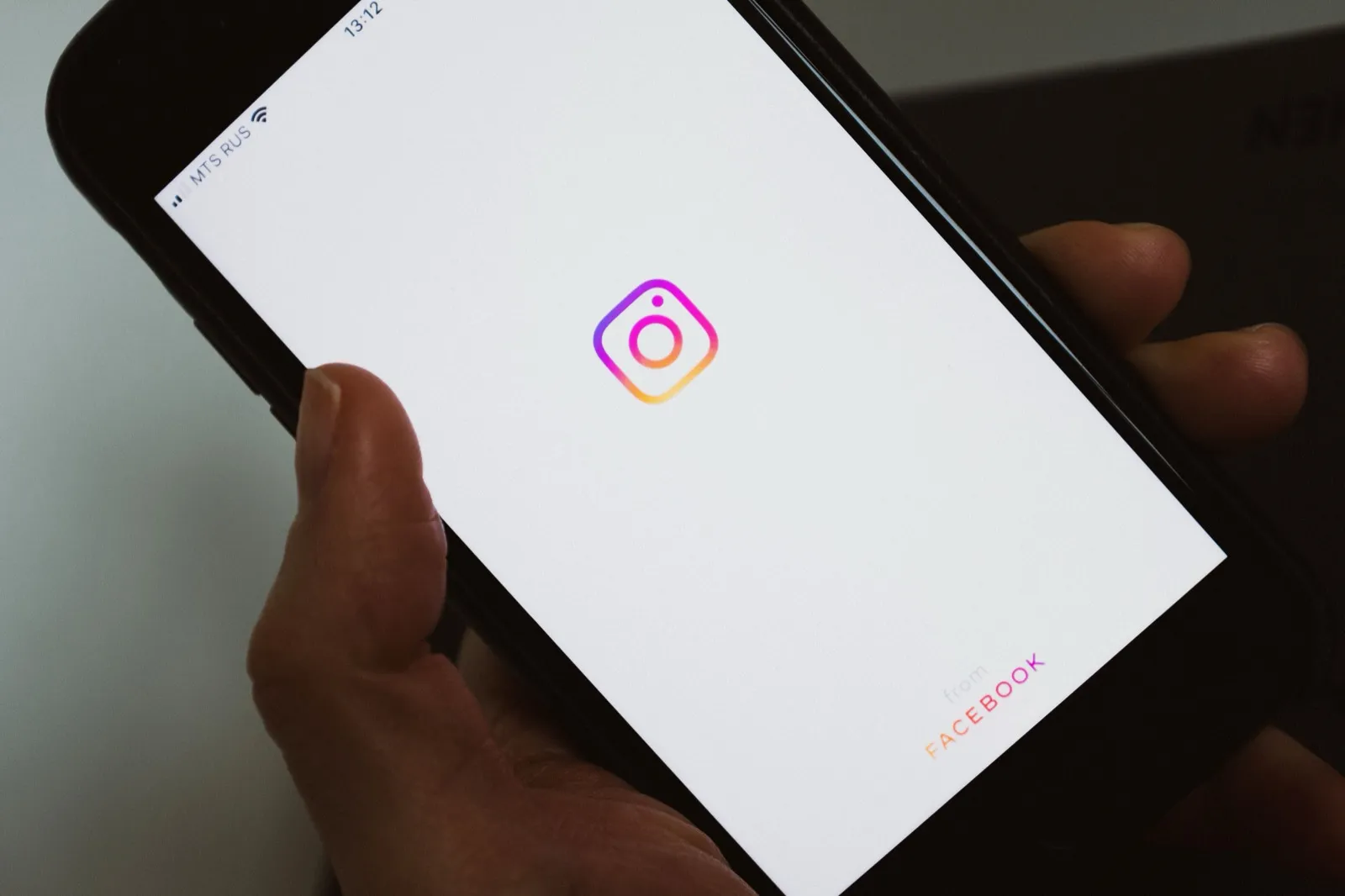 A hand holding a phone showing the Instagram splash screen.
